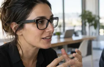 Mujer conversa en una oficina mientras lleva unas gafas inteligentes de audio sin cámara