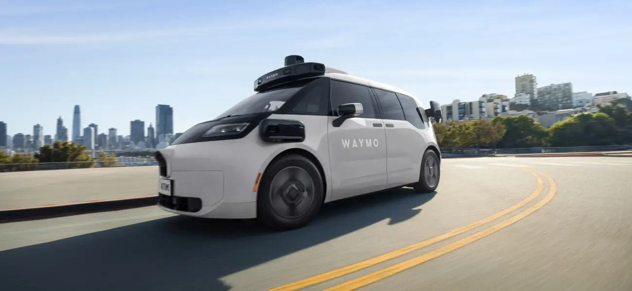 Robotaxi eléctrico Waymo Ojai con sensores de sexta generación circulando por una carretera urbana